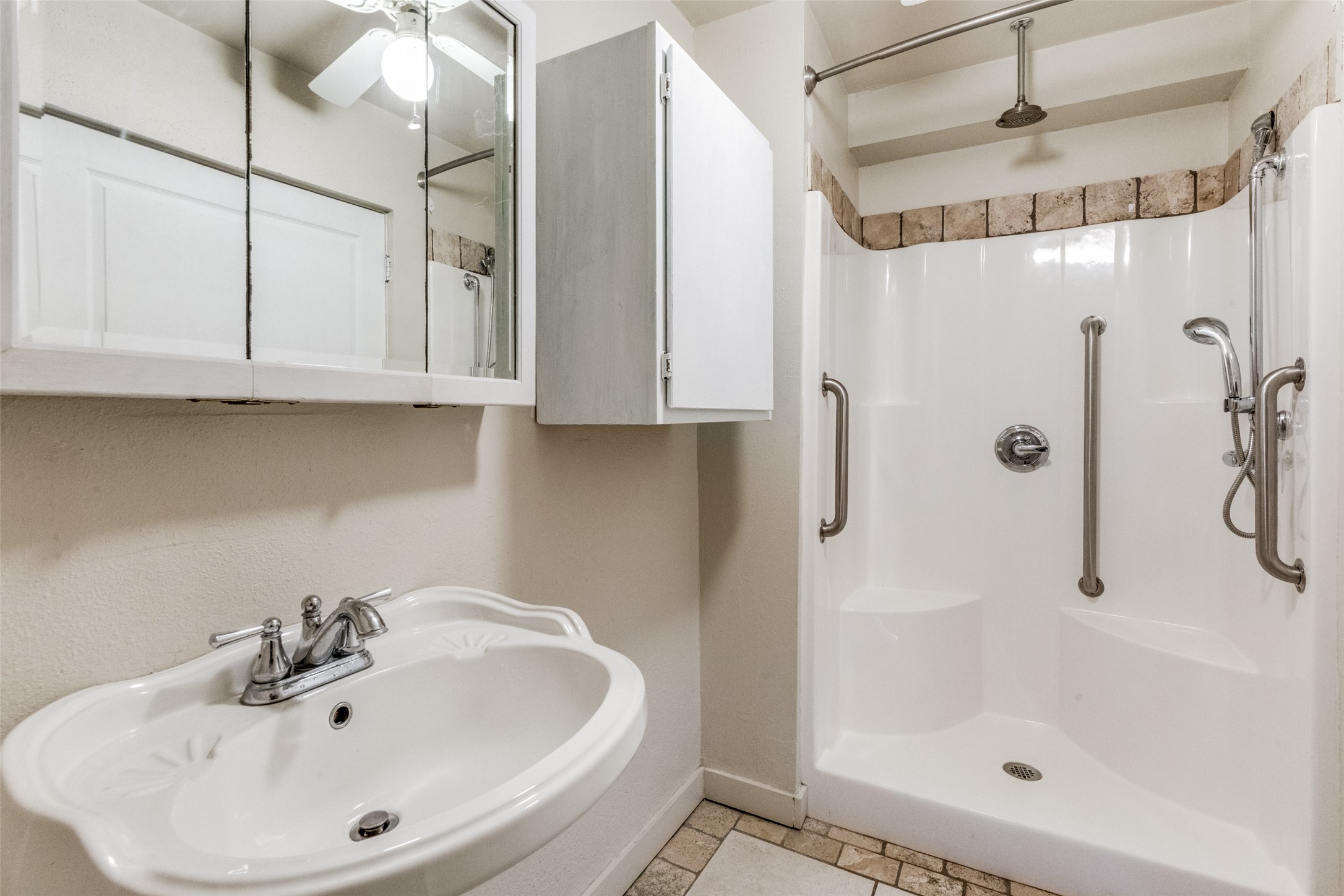 1005 Center Circle Salado, TX 76571 - Photo 12 of 25 The ensuite primary bath features a walk in shower, pedestal sink, and wall mounted cabinets for storage.