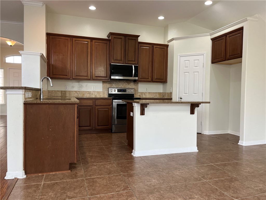 1406 Sacramento Street Portland, TX 78374 - Photo 19 of 35 a kitchen with stainless steel appliances granite countertop a stove top oven a sink a microwave and a refrigerator
