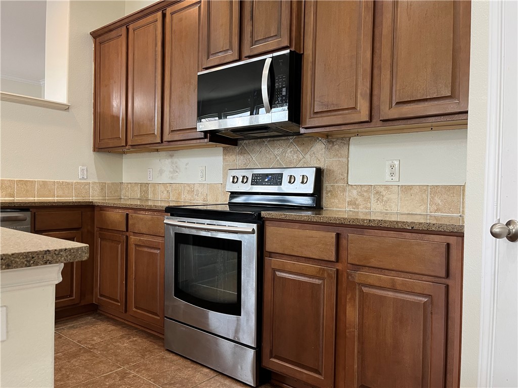 1406 Sacramento Street Portland, TX 78374 - Photo 21 of 35 a kitchen with stainless steel appliances granite countertop wooden cabinets granite counter tops and a stove top oven
