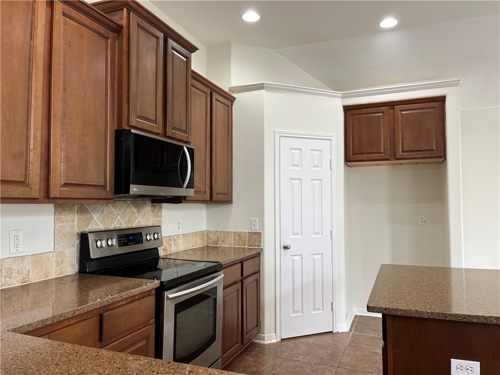 1406 Sacramento Street Portland, TX 78374 - Photo 22 of 35 a kitchen with stainless steel appliances granite countertop a refrigerator stove top oven and sink