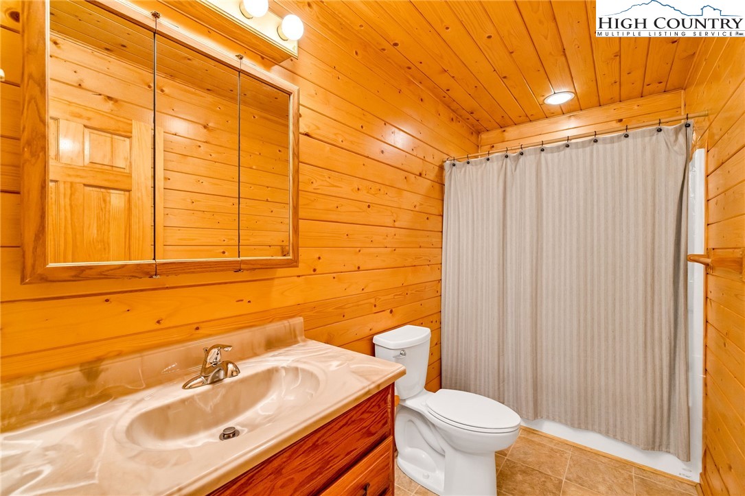 637 River Country Road Piney Creek, NC 28663 - Photo 18 of 49 a bathroom with a sink a toilet and shower curtain