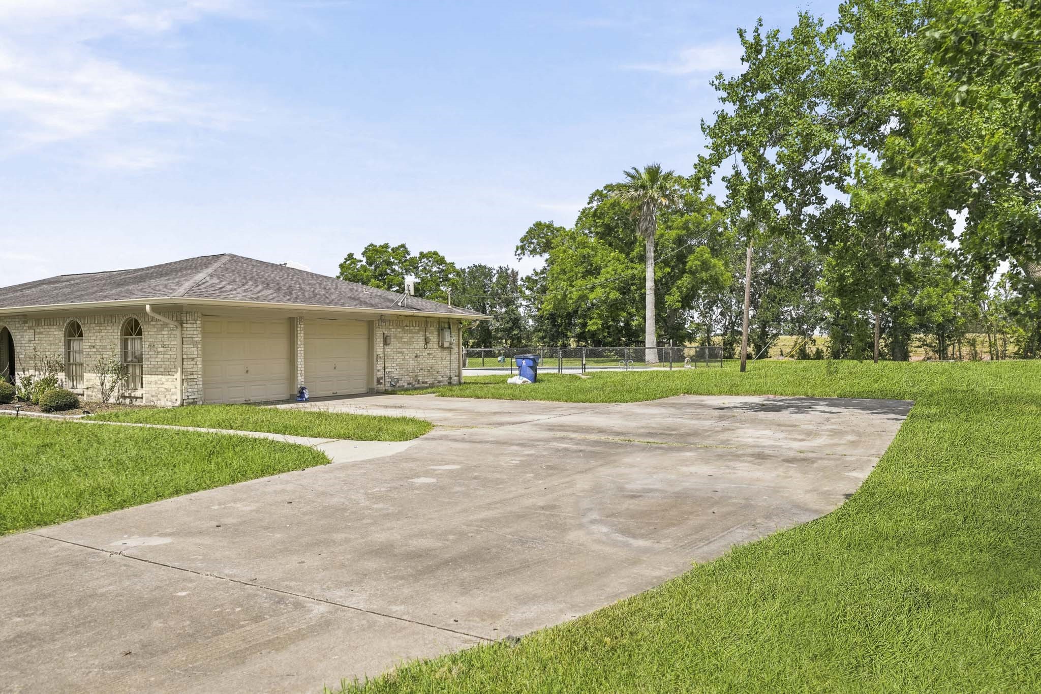 302 Country Road 893 Angleton, TX 77515 - Photo 6 of 26 Large driveway and garage, surrounded by a spacious lawn and mature trees, offering ample outdoor space.