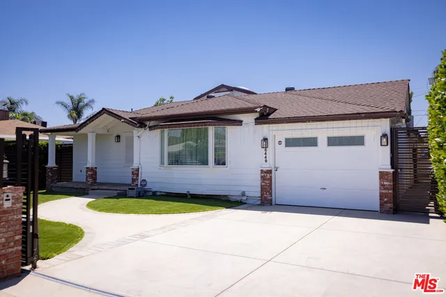 a view of a house with a small yard and a large tree