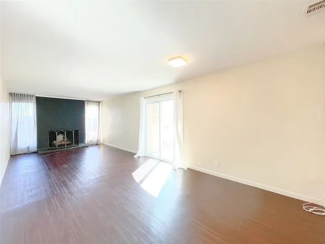 a view of a livingroom with wooden floor and a fireplace