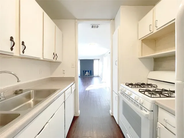 a kitchen with granite countertop a sink cabinets and stainless steel appliances
