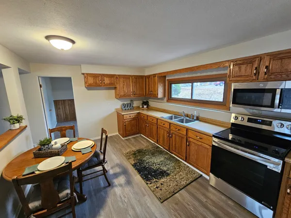 a kitchen with stainless steel appliances granite countertop a stove top oven a sink dishwasher a dining table and chairs with wooden floor