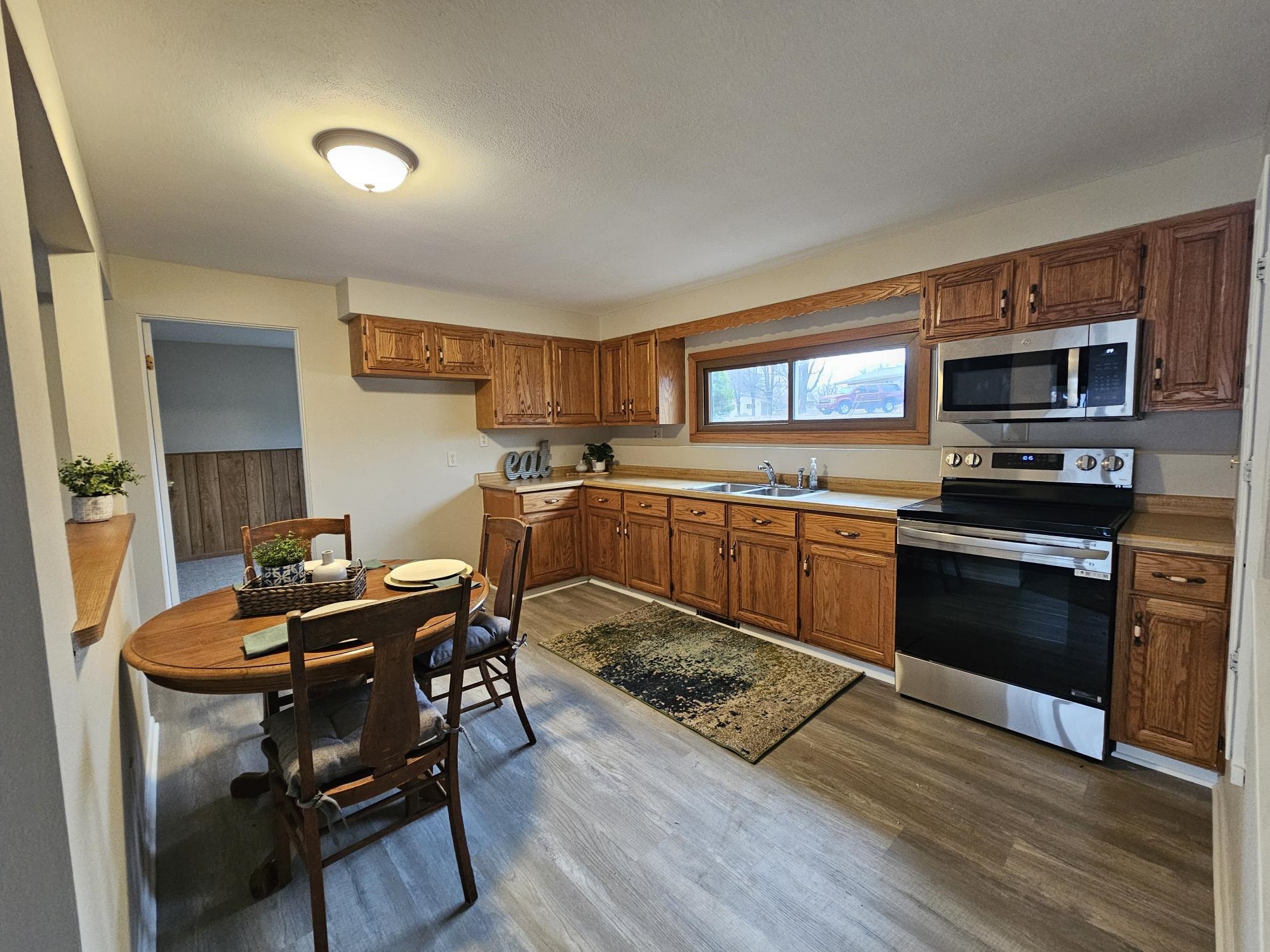 808 Crest View Trail Byron, IL 61010 - Photo 12 of 18 a kitchen with stainless steel appliances granite countertop a stove top oven a sink dishwasher a dining table and chairs with wooden floor
