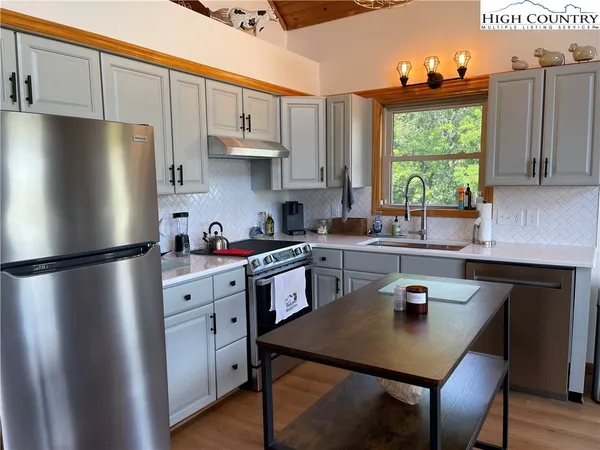 a kitchen with stainless steel appliances a refrigerator a stove a sink a center island and a window