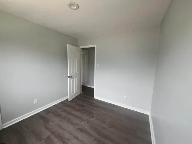 an empty room with wooden floor and white walls