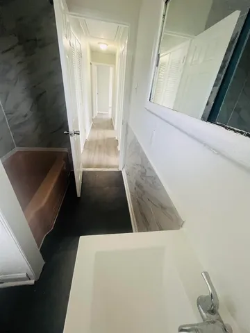 a bathroom with a toilet sink and mirror next to window