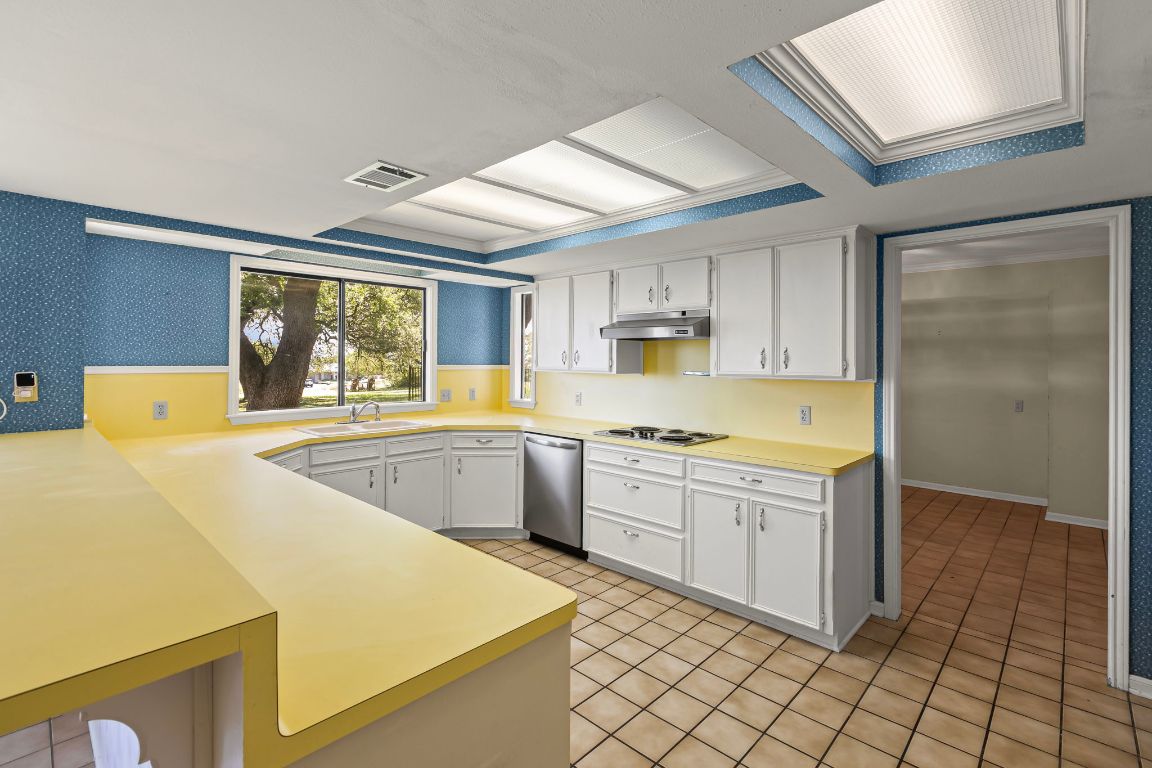 415 Dasher Drive Lakeway, TX 78734 - Photo 14 of 38 a kitchen with stainless steel appliances a stove a sink and white cabinets