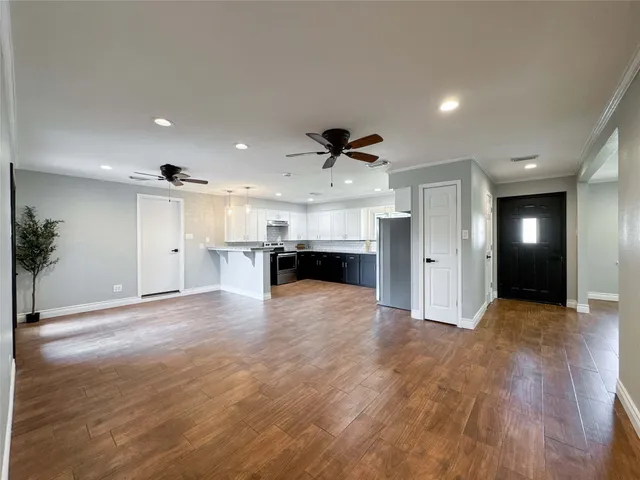 a view of an empty room and kitchen with furniture wooden floor and window