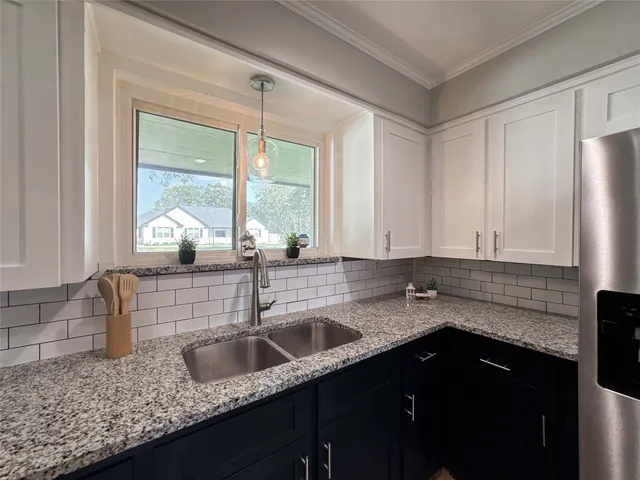 a kitchen with granite countertop a sink a refrigerator and window
