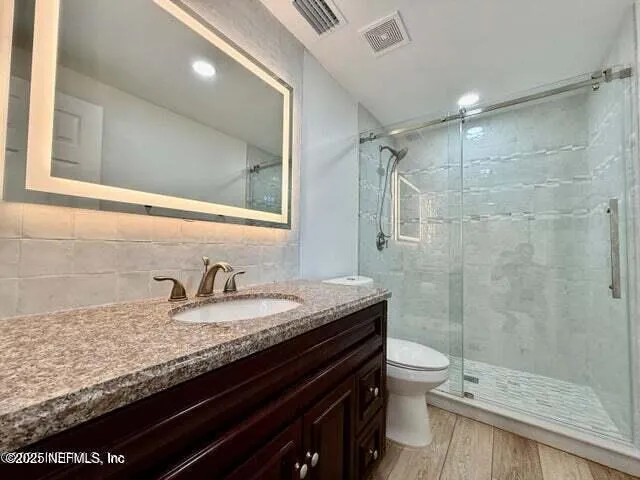 a bathroom with a granite countertop sink a toilet a mirror and shower