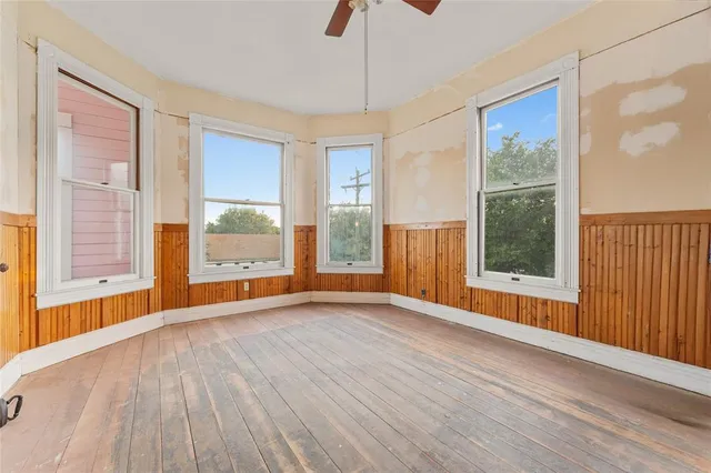 a view of an empty room with a window and wooden floor