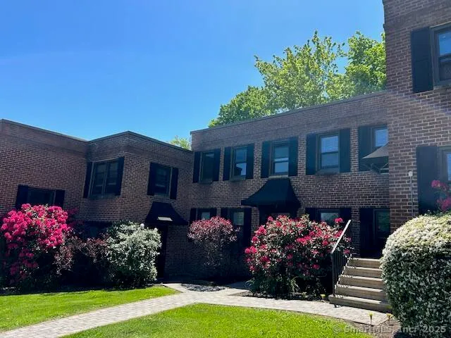a front view of house and yard with beautiful flowers and green space