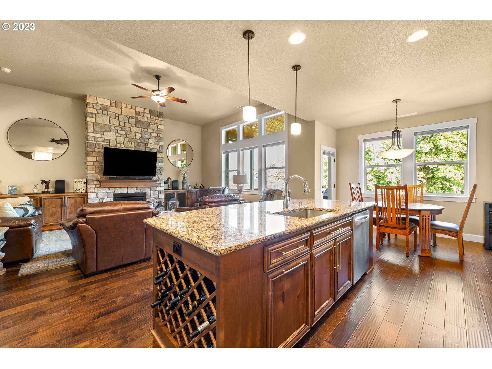 1845 South Harrier Road Ridgefield, WA 98642 - Photo 12 of 28 a large kitchen with stainless steel appliances kitchen island granite countertop a sink dishwasher a dining table and chairs with wooden floor