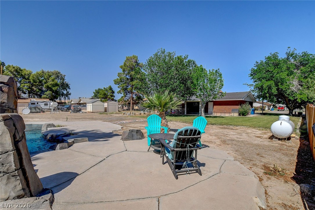 3765 Berkeley Street Logandale, NV 89021 - Photo 77 of 87 This spacious yard features a concrete patio, lush trees, and a refreshing pool, creating an ideal outdoor retreat.