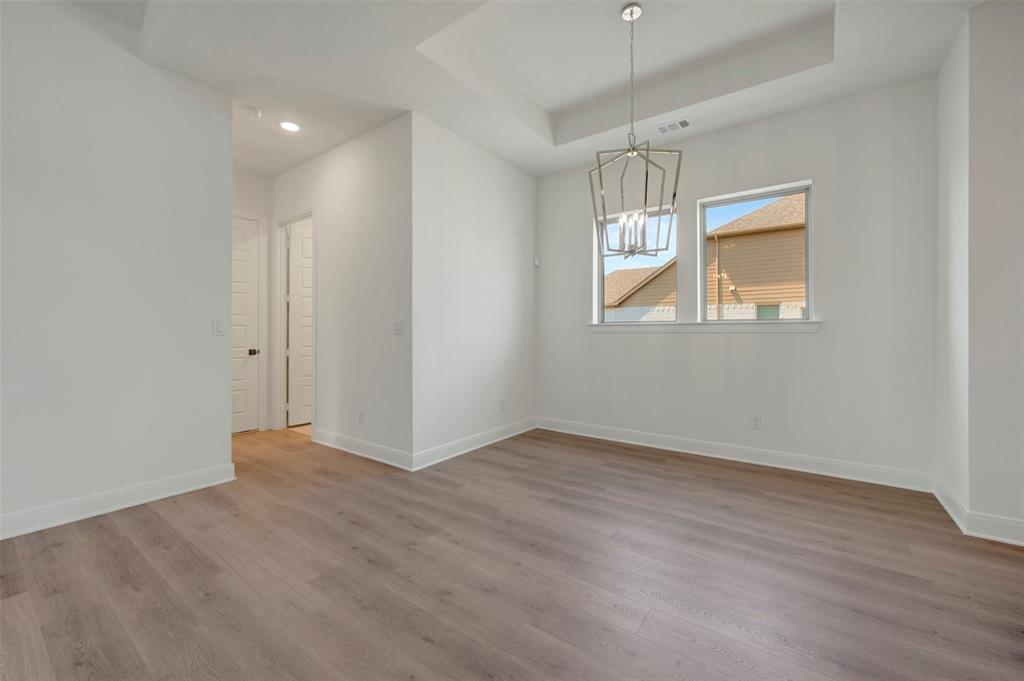 1908 Cola Drive Van Alstyne, TX 75495 - Photo 20 of 29 Spacious room featuring wood-finish flooring, a tray ceiling, and a contemporary chandelier