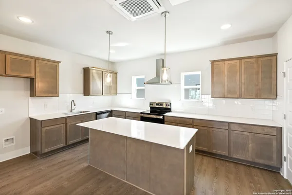 a kitchen with stainless steel appliances granite countertop a sink a stove and a wooden floors