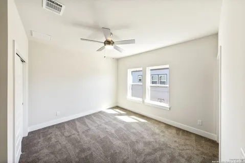 an empty room with windows and fan