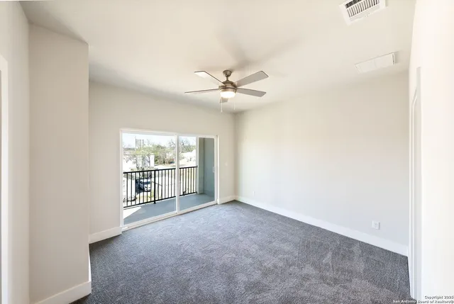 an empty room with windows and ceiling fan