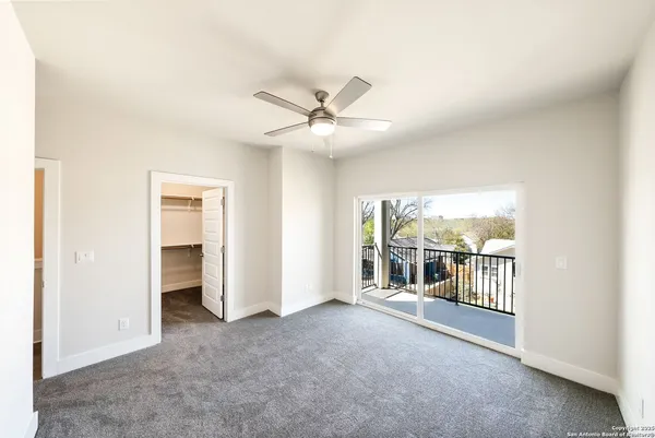 an empty room with chandelier fan and windows