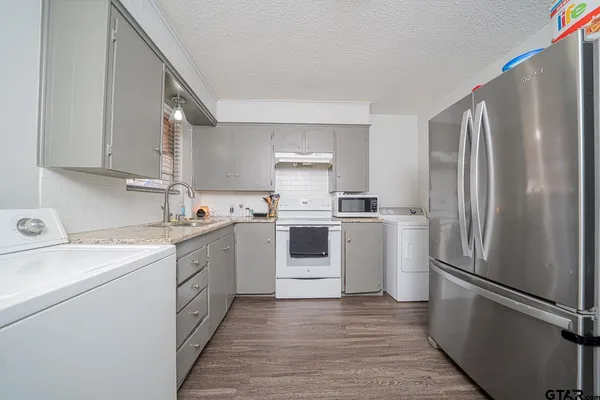 a kitchen with a white refrigerator sink and cabinets