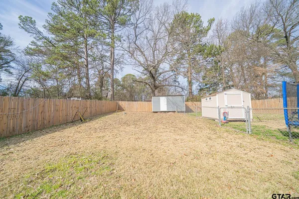 a backyard of a house with a large tree and wooden fence