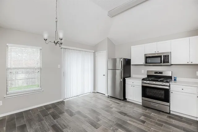 a kitchen with stainless steel appliances a stove a refrigerator and a microwave