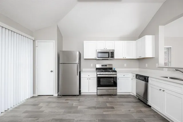 a kitchen with stainless steel appliances granite countertop a refrigerator stove a sink and dishwasher with white cabinets