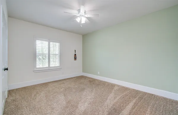 en empty room with windows and ceiling fan