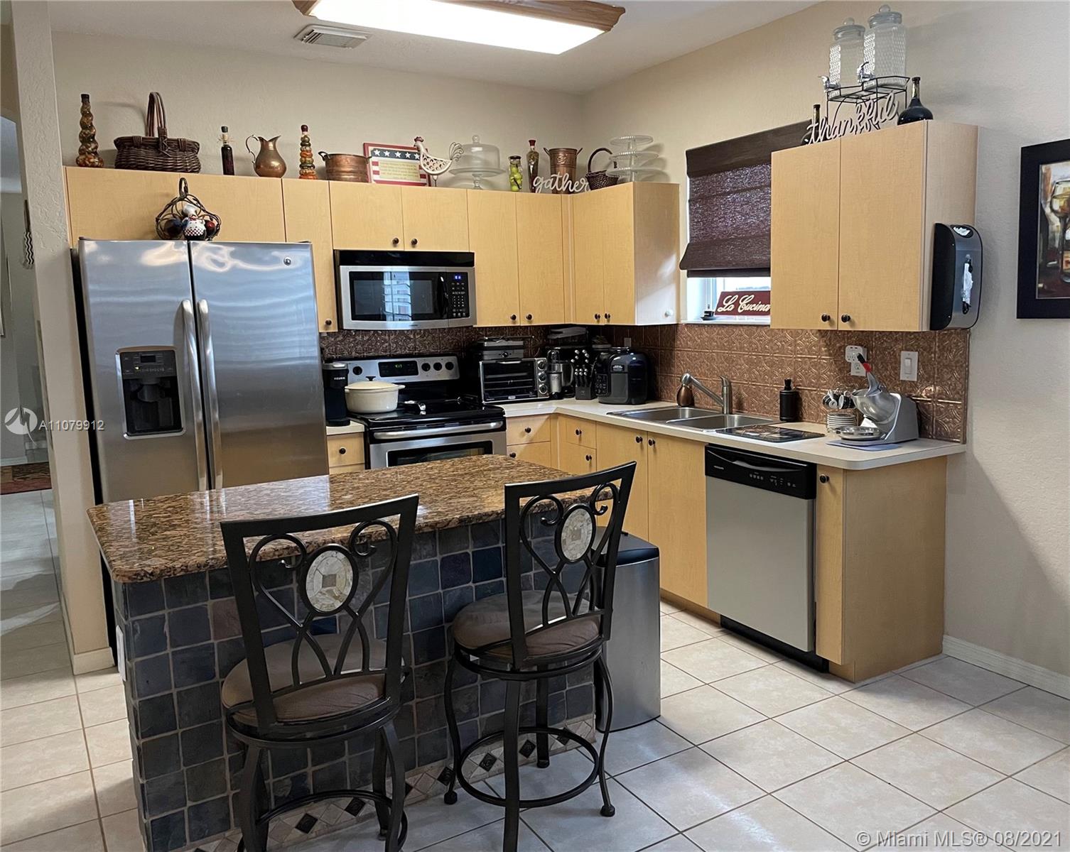 West Kendall Miami, FL 33193 - Photo 5 of 8 a kitchen with stainless steel appliances a sink a microwave a refrigerator and chairs