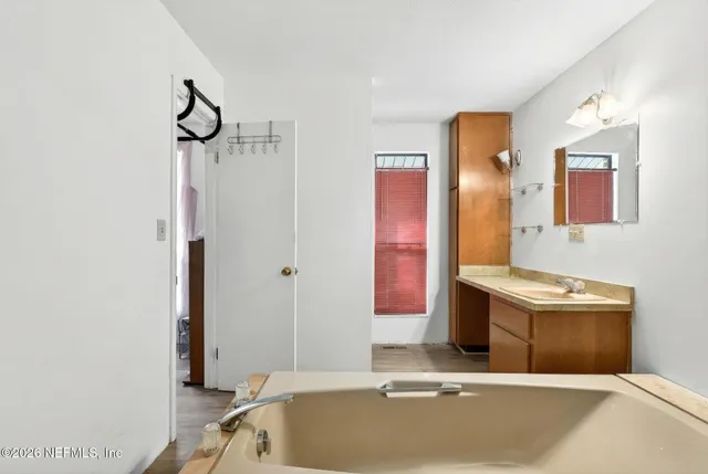 a bathroom with a tub sink and mirror