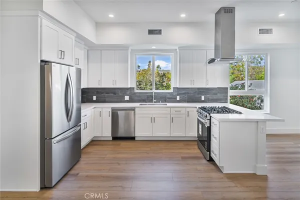 a kitchen with stainless steel appliances a stove a sink cabinets and a window