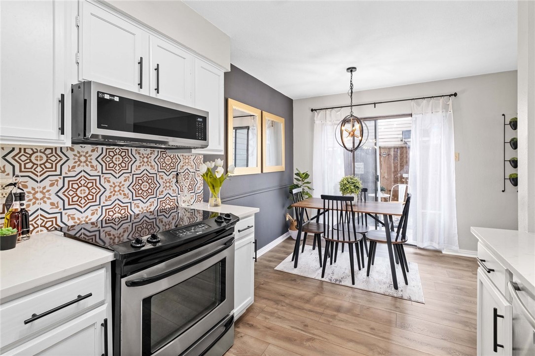 a kitchen with granite countertop a stove chairs and microwave