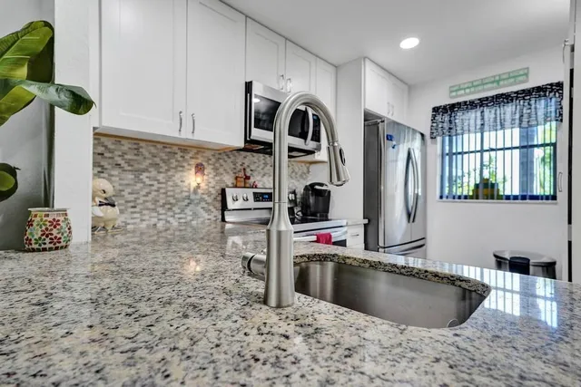 a kitchen with stainless steel appliances granite countertop a sink a stove and a refrigerator