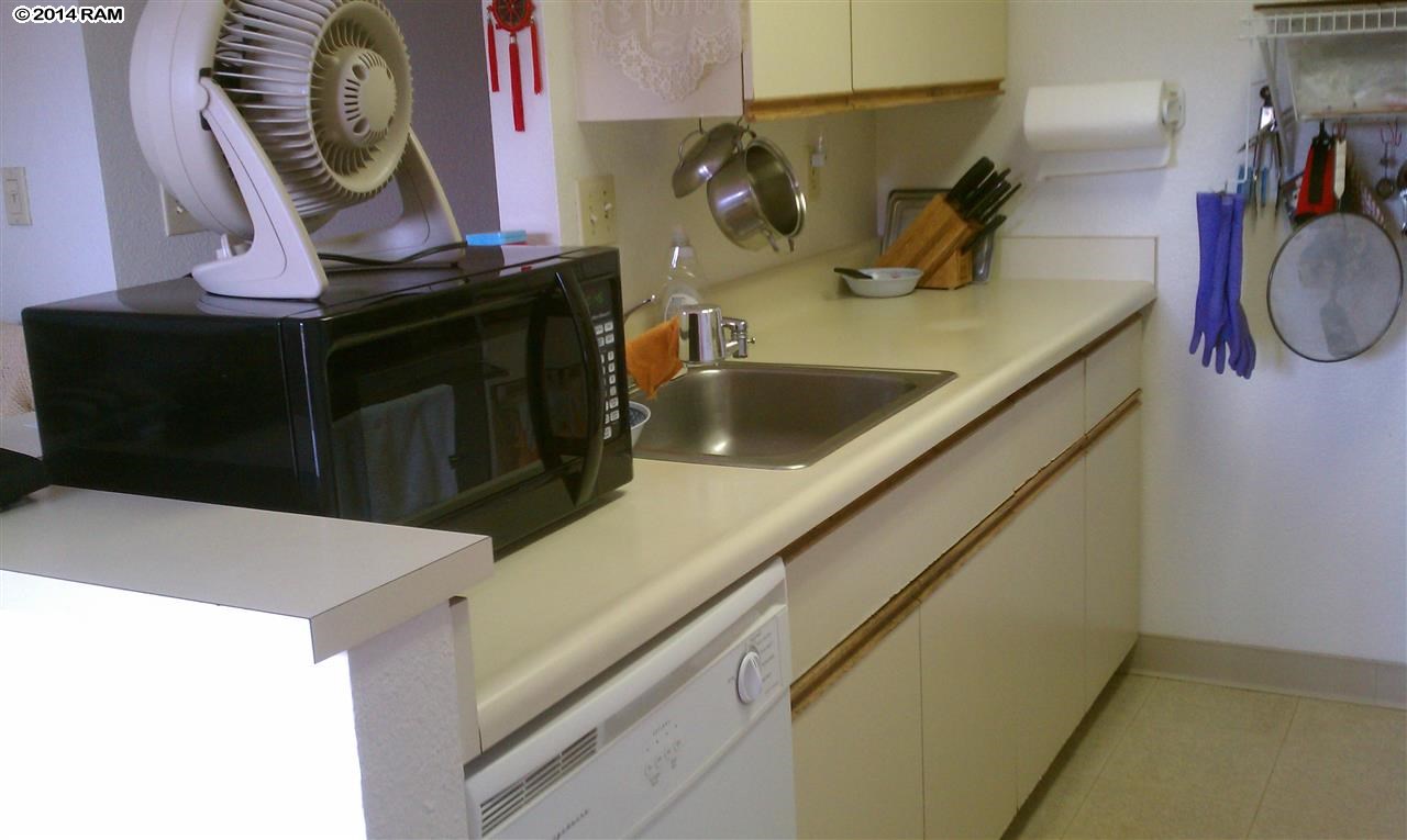 140 Uwapo Road, Unit 1201 Kihei, HI 96753 - Photo 2 of 8 a kitchen with a sink and a stove with wooden floor