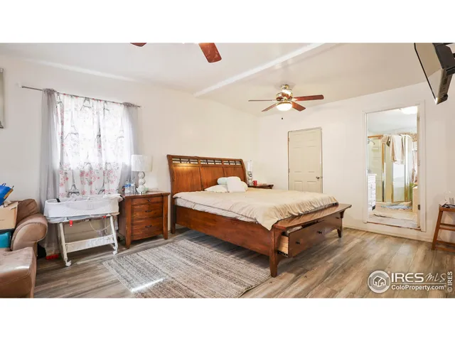 a bedroom with a bed couch chandelier and a window