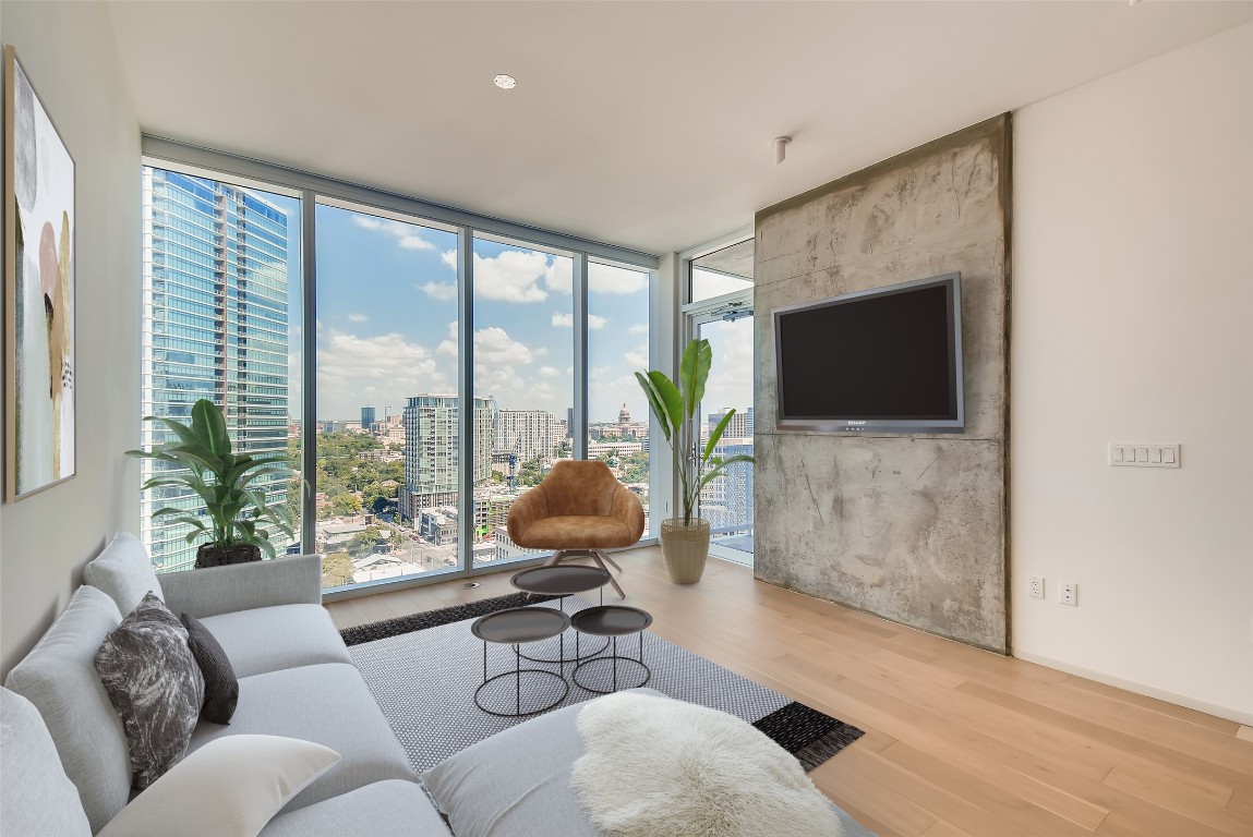a living room with furniture floor to ceiling window and a flat screen tv