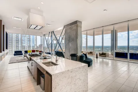 a kitchen with a stove a sink a counter top space and living room filled with furniture