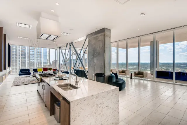 a kitchen with a stove a sink a counter top space and living room filled with furniture