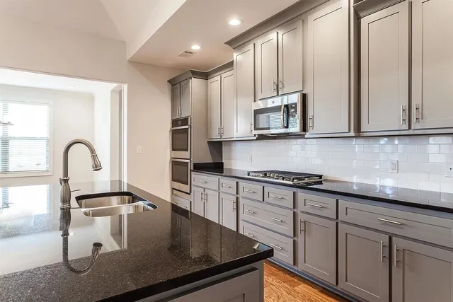 a kitchen with stainless steel appliances granite countertop a stove a sink and white cabinets