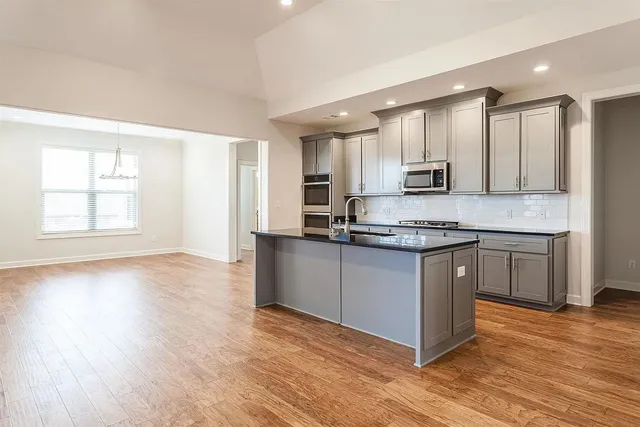 a kitchen with granite countertop a stove and a sink with wooden floor