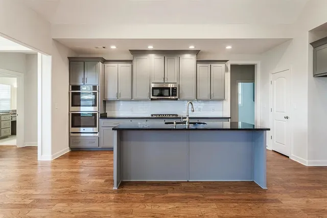 a kitchen with stainless steel appliances granite countertop a stove a sink and a microwave
