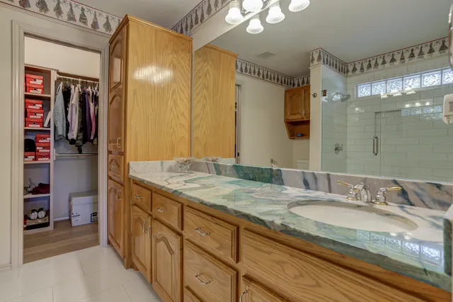 a bathroom with a granite countertop sink a mirror and shower