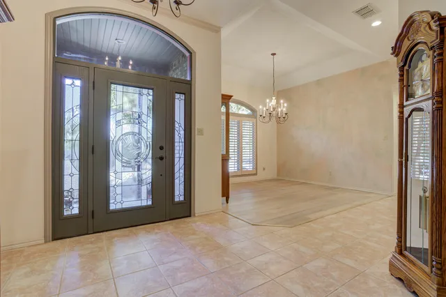 a view of an empty room with window and chandelier