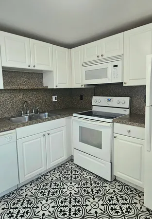 a kitchen with granite countertop white cabinets and white appliances