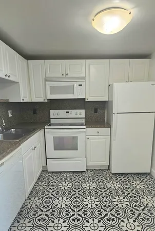 a kitchen with a stove a refrigerator and white cabinets