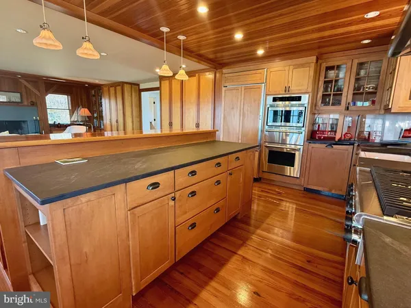 a dining room with wooden floor a large window and stainless steel appliances